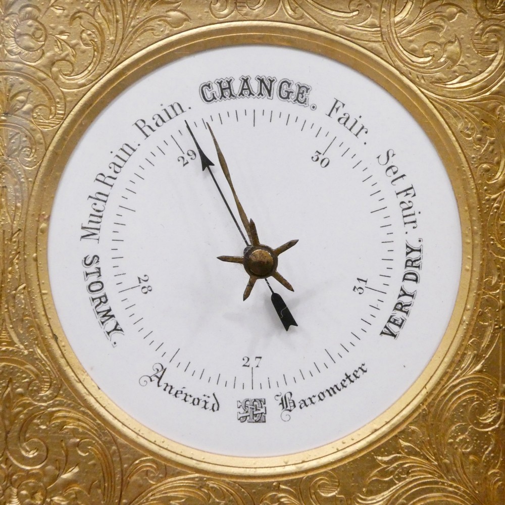 An Edwardian rectangular ebonised wooden mantel clock and barometer unit with twin white circular dials set into a scroll-engraved brass plate. View IV