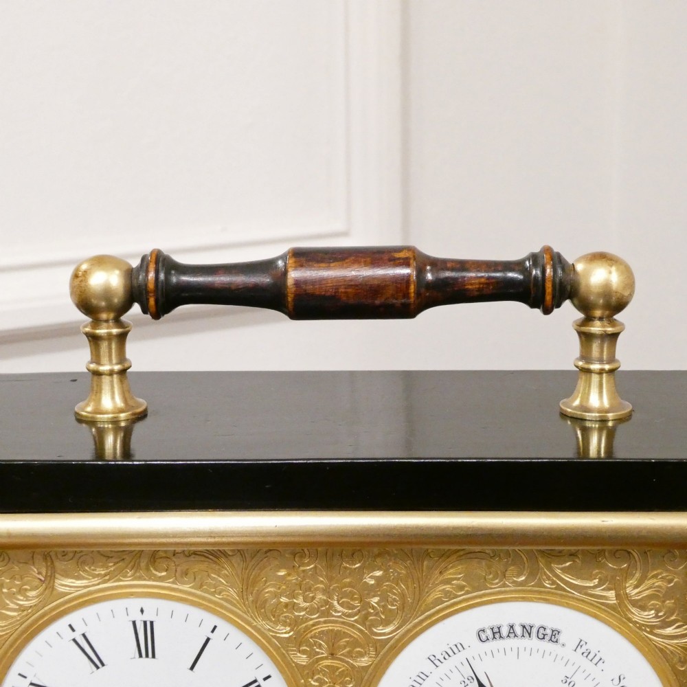 An Edwardian rectangular ebonised wooden mantel clock and barometer unit with twin white circular dials set into a scroll-engraved brass plate. View VI
