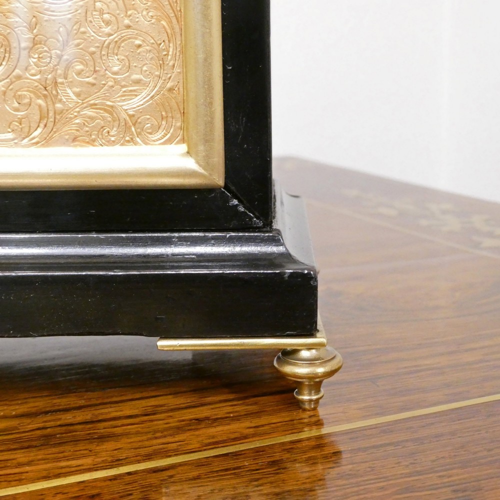An Edwardian rectangular ebonised wooden mantel clock and barometer unit with twin white circular dials set into a scroll-engraved brass plate. View VIII