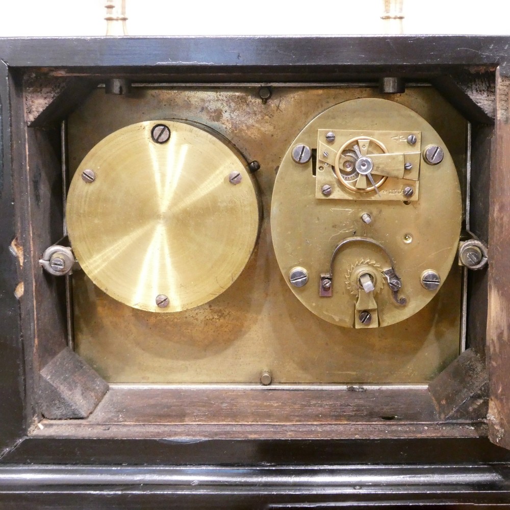 An Edwardian rectangular ebonised wooden mantel clock and barometer unit with twin white circular dials set into a scroll-engraved brass plate. View XII