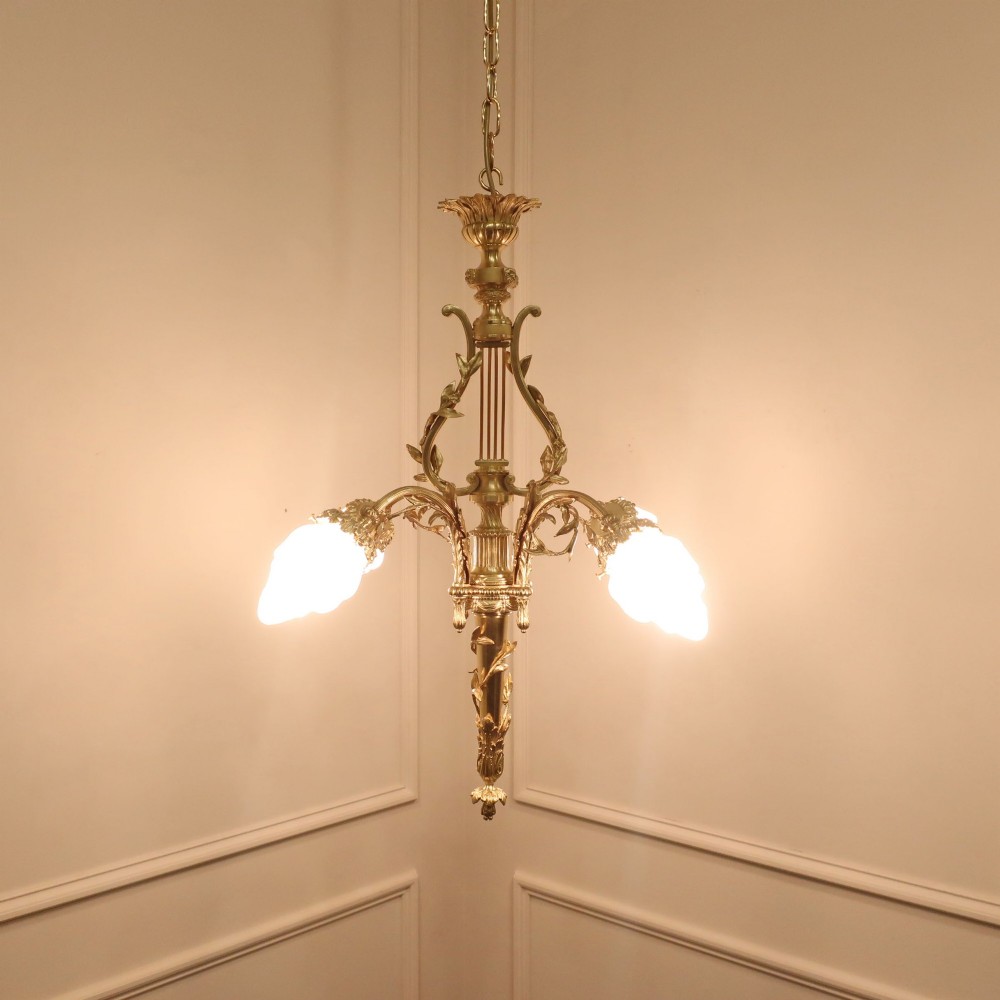 A French Neoclassical style gilt bronze chandelier featuring a central lyre-shaped stem and two outward-curving arms with frosted glass shades. View II
