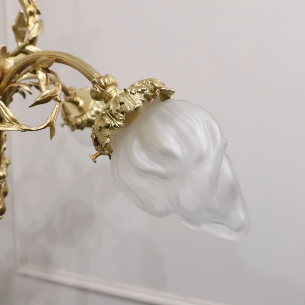 A French Neoclassical style gilt bronze chandelier featuring a central lyre-shaped stem and two outward-curving arms with frosted glass shades. View V
