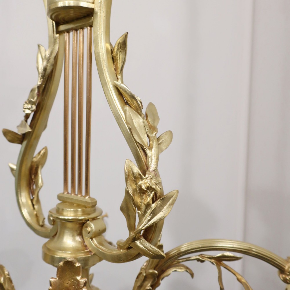 A French Neoclassical style gilt bronze chandelier featuring a central lyre-shaped stem and two outward-curving arms with frosted glass shades. View VII