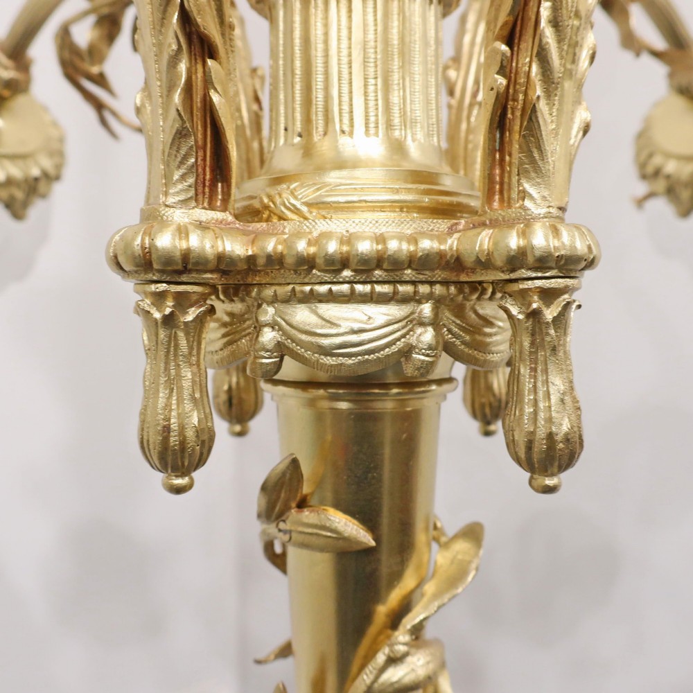 A French Neoclassical style gilt bronze chandelier featuring a central lyre-shaped stem and two outward-curving arms with frosted glass shades. View X