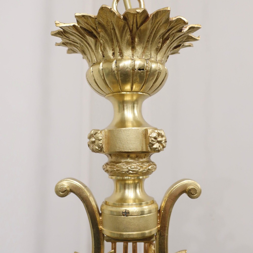 A French Neoclassical style gilt bronze chandelier featuring a central lyre-shaped stem and two outward-curving arms with frosted glass shades. View XIV