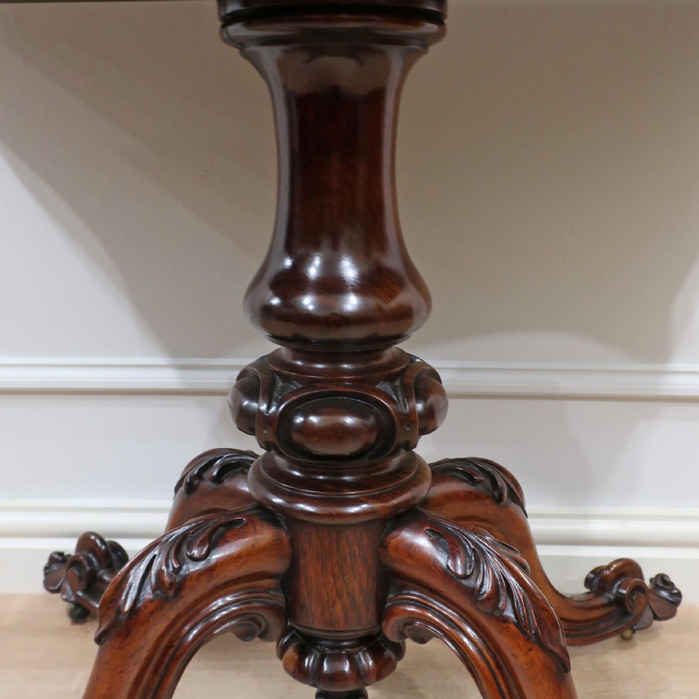 A Victorian rosewood side table featuring a serpentine fold-over top mounted on a central carved pedestal with four scroll-footed legs. View VI