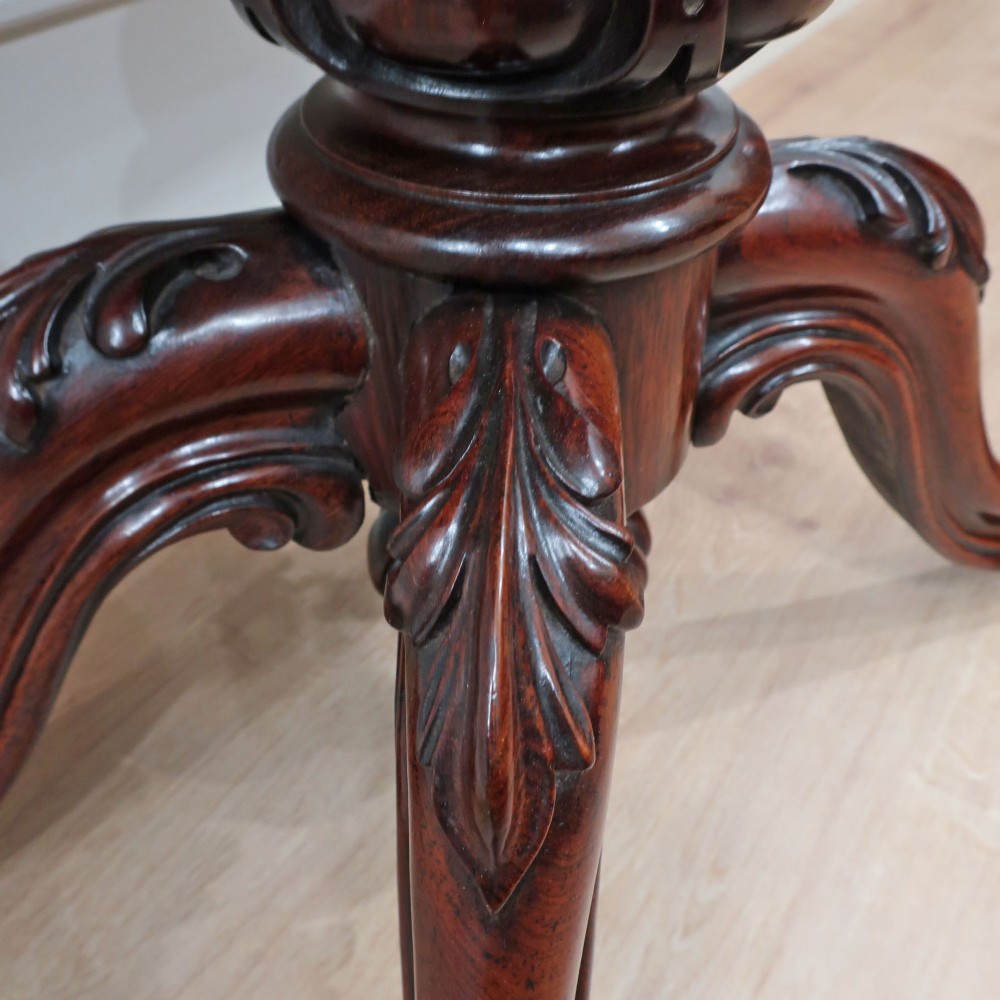 A Victorian rosewood side table featuring a serpentine fold-over top mounted on a central carved pedestal with four scroll-footed legs. View VIII