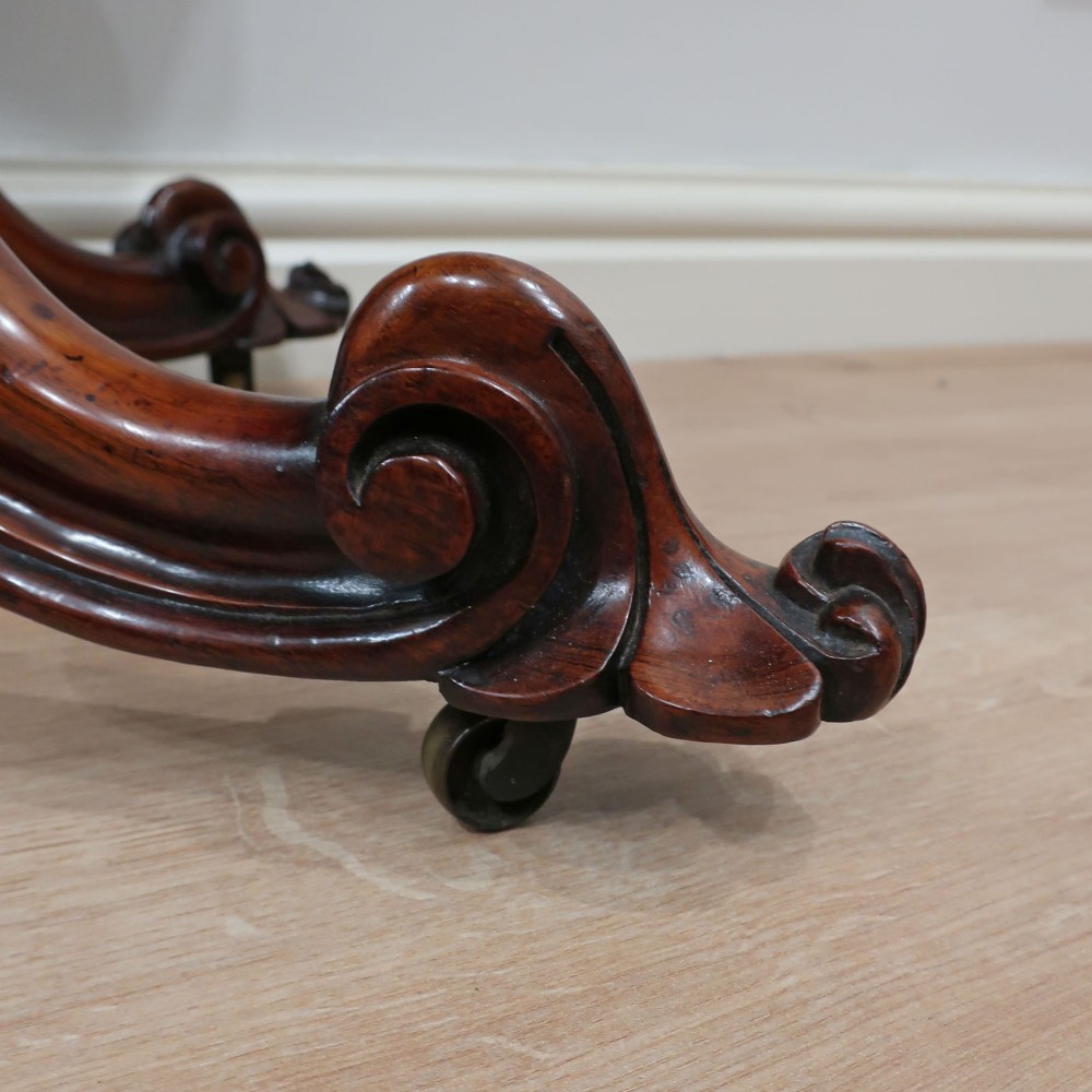 A Victorian rosewood side table featuring a serpentine fold-over top mounted on a central carved pedestal with four scroll-footed legs. View X