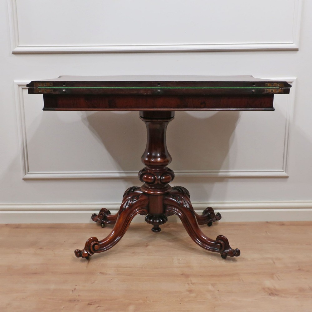 A Victorian rosewood side table featuring a serpentine fold-over top mounted on a central carved pedestal with four scroll-footed legs. View XIV