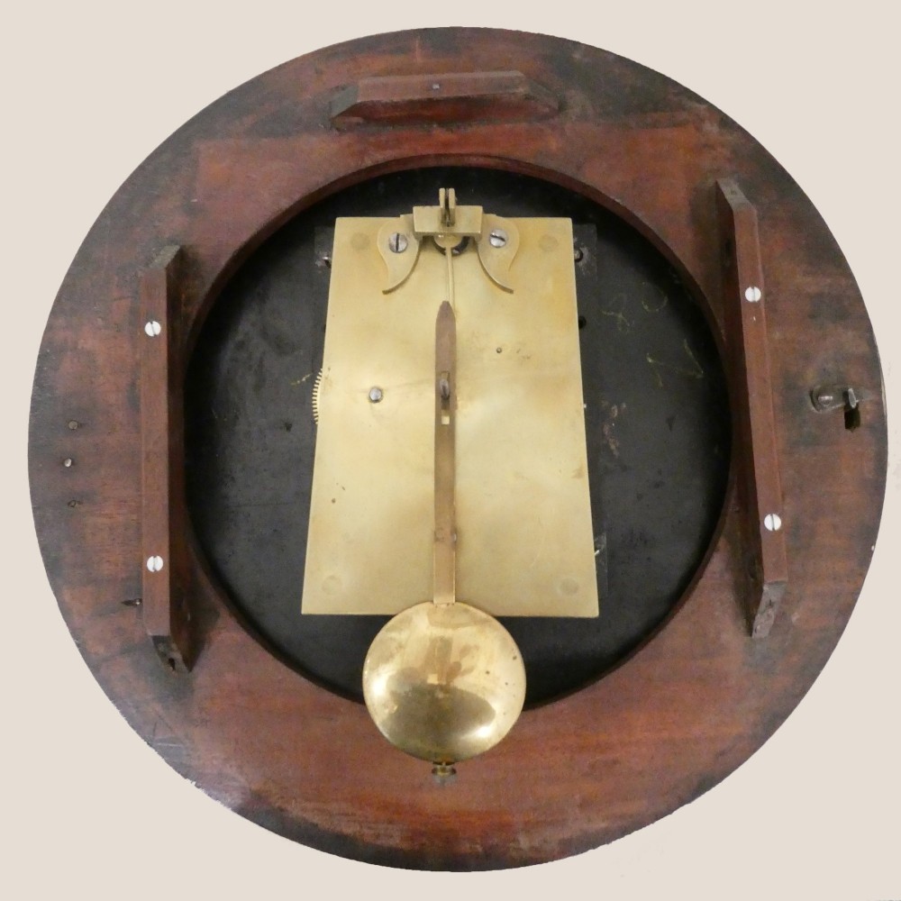 A circular Georgian wall clock featuring a cream dial with black Roman numerals, blued steel hands, a polished brass bezel, and a dark mahogany wood surround. View VII