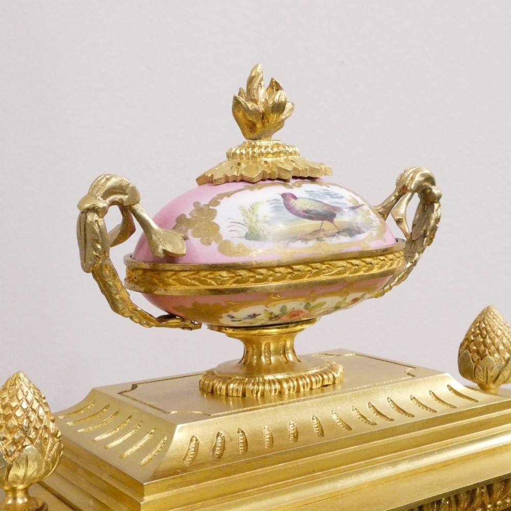 An antique French gilt bronze mantel clock featuring hand-painted pink porcelain panels, a porcelain urn finial, and an enamel dial with Roman numerals. View IX