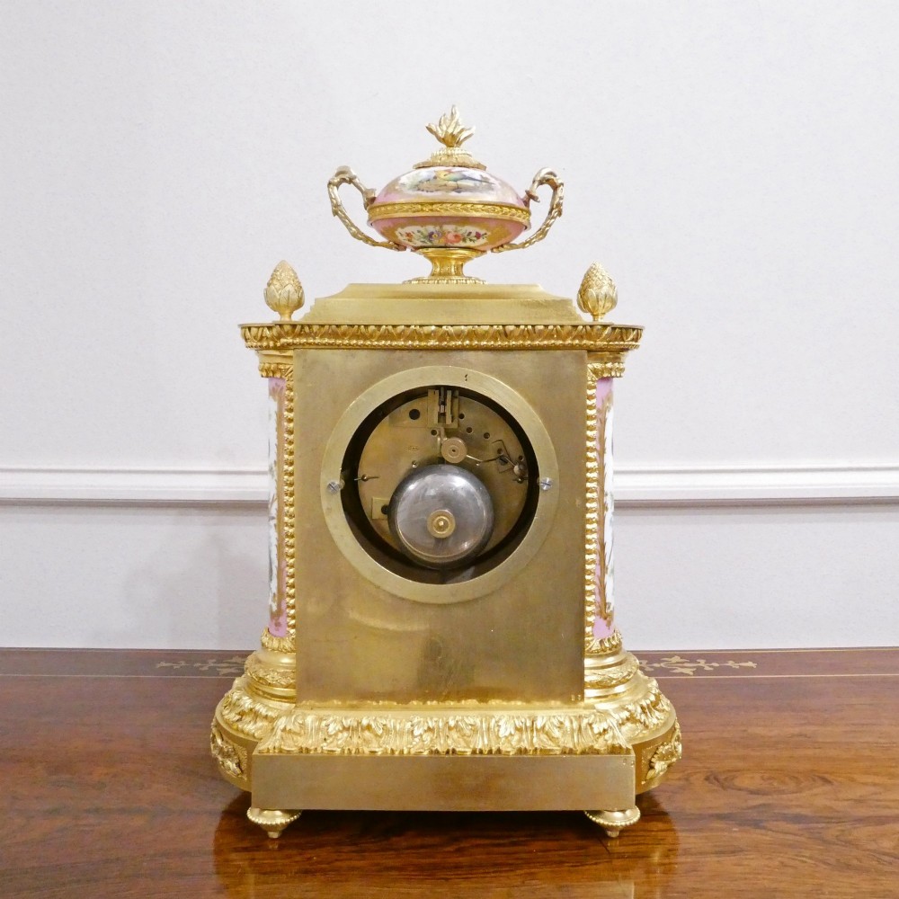 An antique French gilt bronze mantel clock featuring hand-painted pink porcelain panels, a porcelain urn finial, and an enamel dial with Roman numerals. View XIII