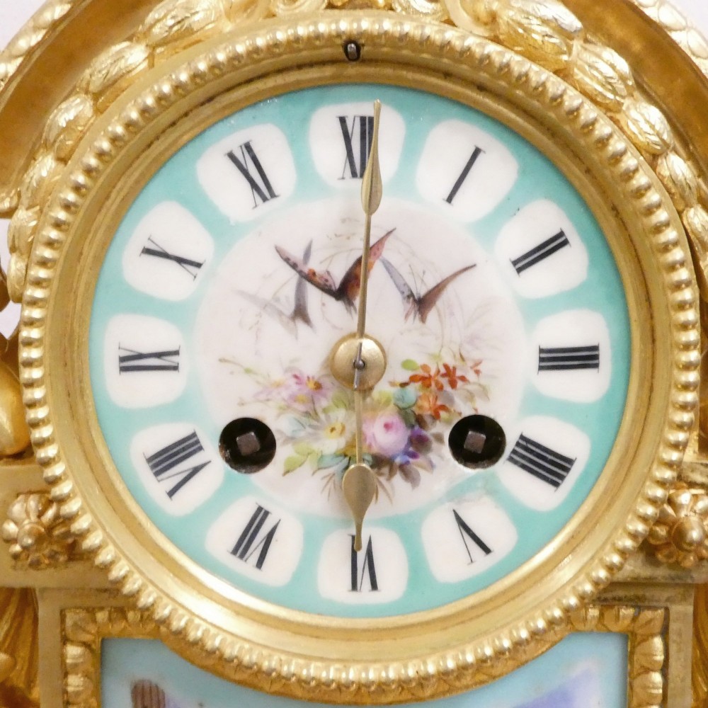 A French 19th-century gilt bronze mantel clock featuring light blue hand-painted porcelain panels, sculpted putti, an urn finial, and an enamel Roman numeral dial. View III