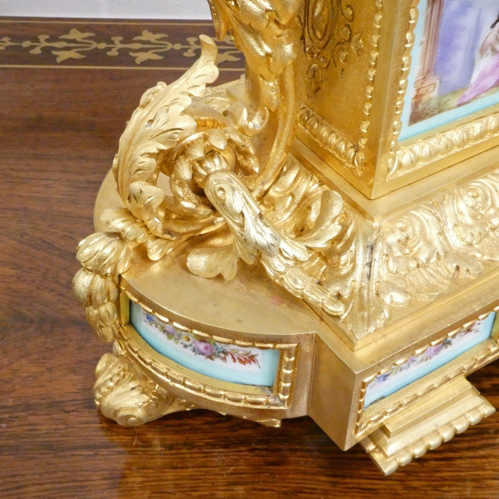 A French 19th-century gilt bronze mantel clock featuring light blue hand-painted porcelain panels, sculpted putti, an urn finial, and an enamel Roman numeral dial. View VII