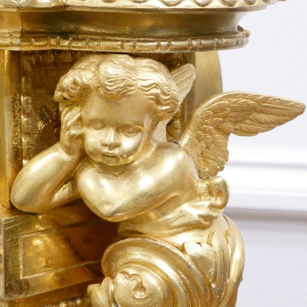 A French 19th-century gilt bronze mantel clock featuring light blue hand-painted porcelain panels, sculpted putti, an urn finial, and an enamel Roman numeral dial. View IX