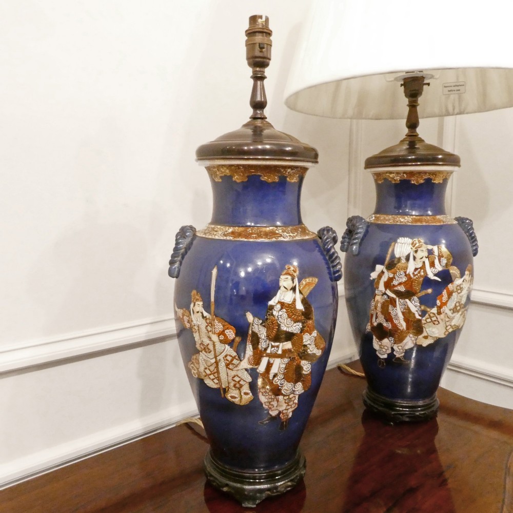 A pair of cobalt blue Japanese Satsuma porcelain table lamps decorated with gilded hand-painted figures and fitted with brass mountings and a cream pleated shade. View II