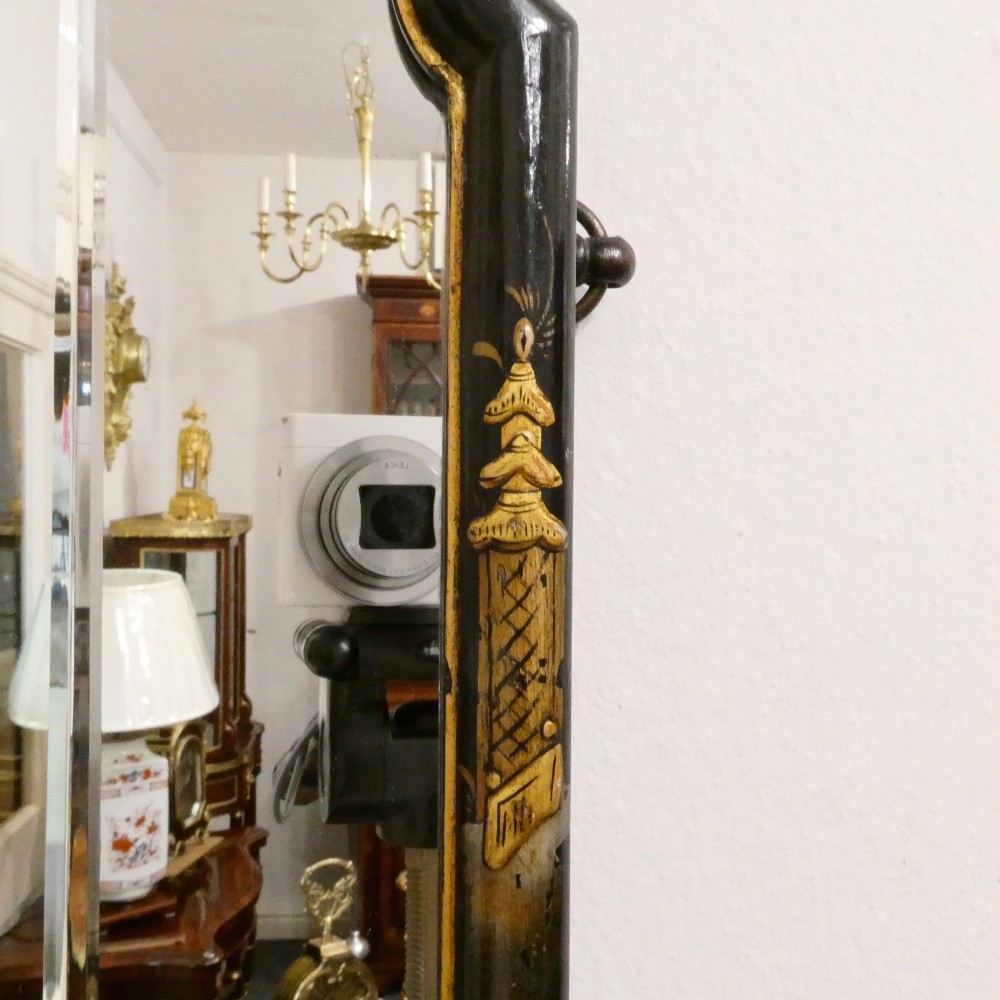 An arched wall mirror with a dark lacquered frame featuring gilded Chinoiserie motifs and segmented glass plates. View IV