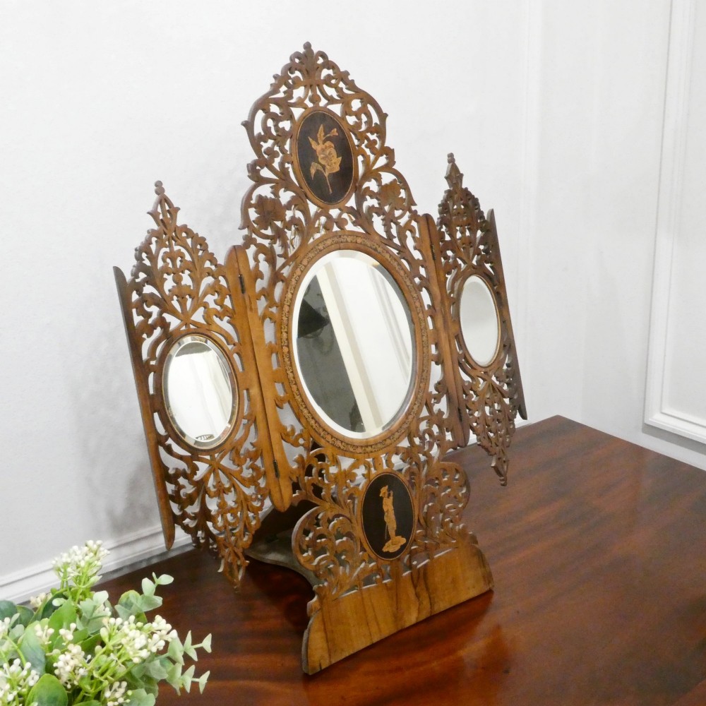 A fretted walnut triptych dressing table mirror featuring central oval glass plates surrounded by openwork carved scroll patterns and inlaid timber panels. View II