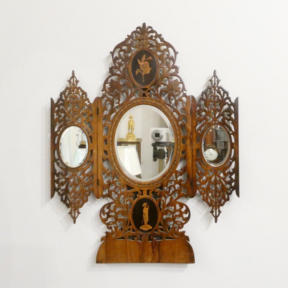 A fretted walnut triptych dressing table mirror featuring central oval glass plates surrounded by openwork carved scroll patterns and inlaid timber panels. View X