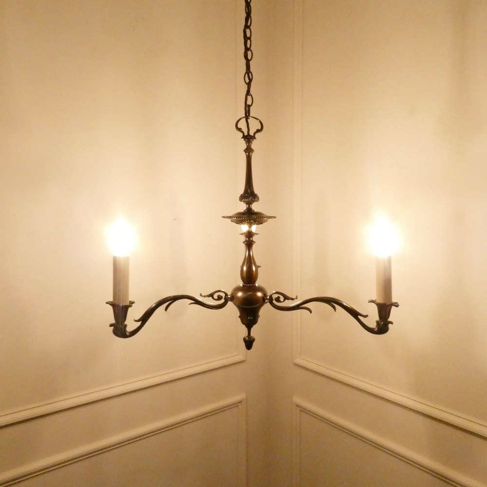 An early 20th-century Dutch bronze two-light chandelier featuring a baluster-turned central stem and curved scrolling arms. View II