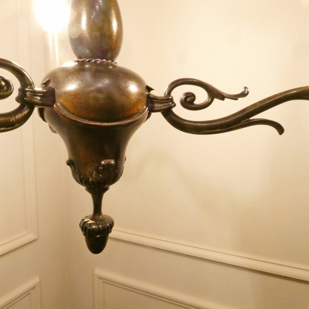An early 20th-century Dutch bronze two-light chandelier featuring a baluster-turned central stem and curved scrolling arms. View IV