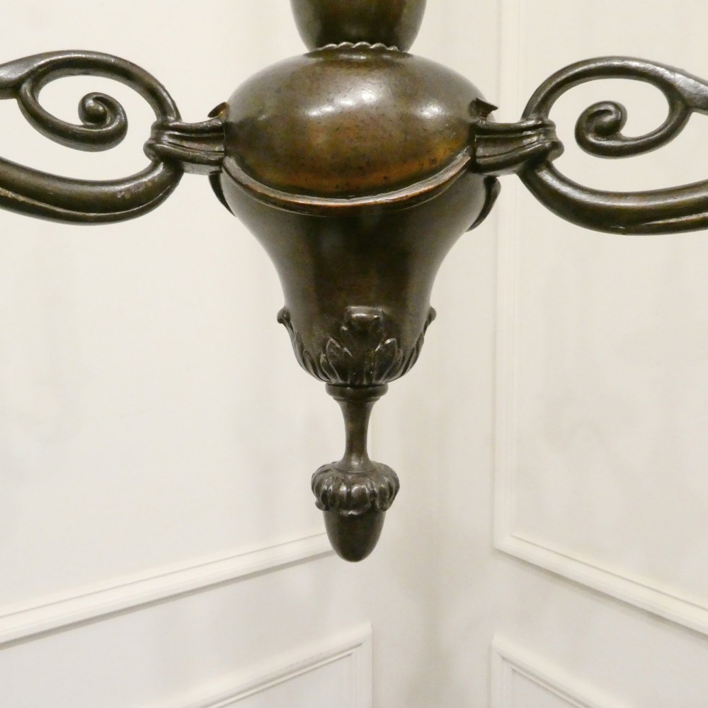 An early 20th-century Dutch bronze two-light chandelier featuring a baluster-turned central stem and curved scrolling arms. View V