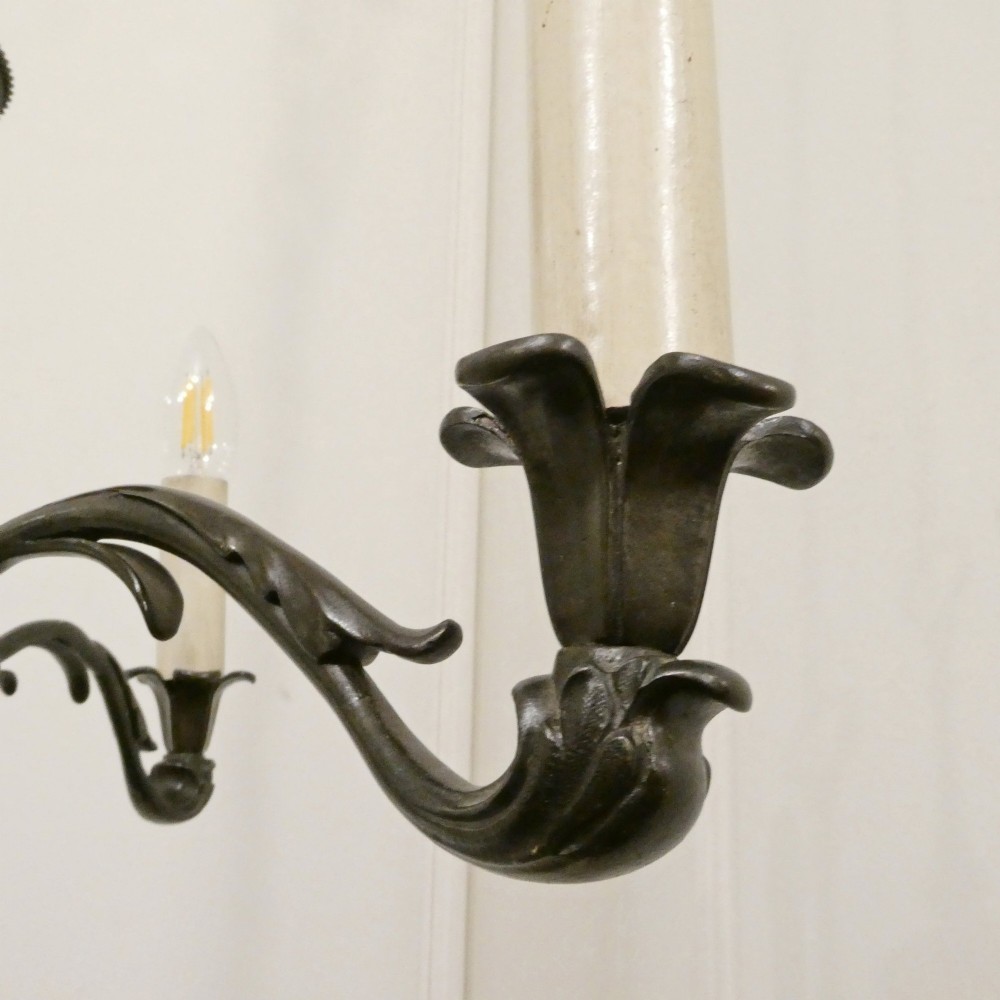 An early 20th-century Dutch bronze two-light chandelier featuring a baluster-turned central stem and curved scrolling arms. View X