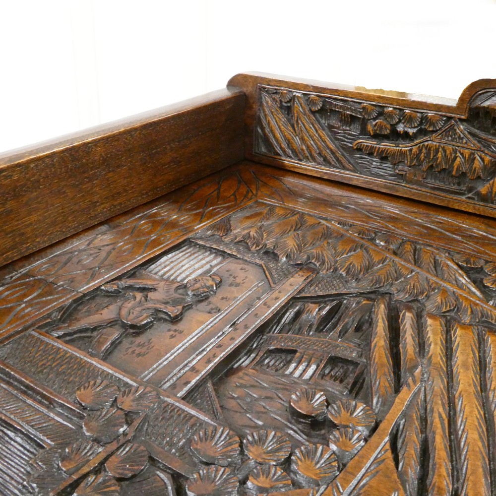 A tall early twentieth-century camphor wood chest of drawers featuring elaborate relief-carved oriental landscapes on the drawer fronts and side panels. View VII