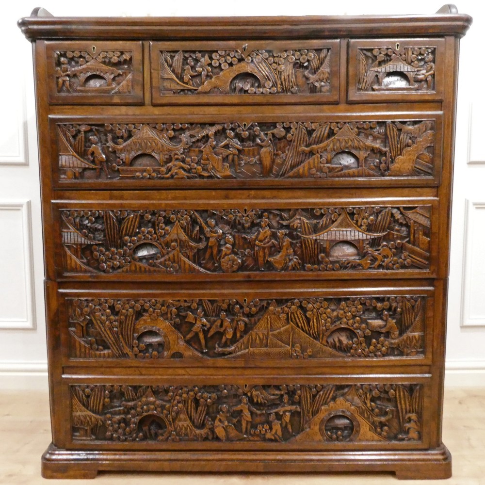 A tall early twentieth-century camphor wood chest of drawers featuring elaborate relief-carved oriental landscapes on the drawer fronts and side panels. View VIII