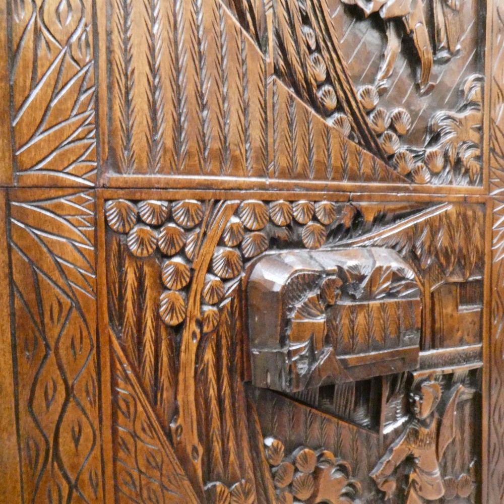 A tall early twentieth-century camphor wood chest of drawers featuring elaborate relief-carved oriental landscapes on the drawer fronts and side panels. View XIII