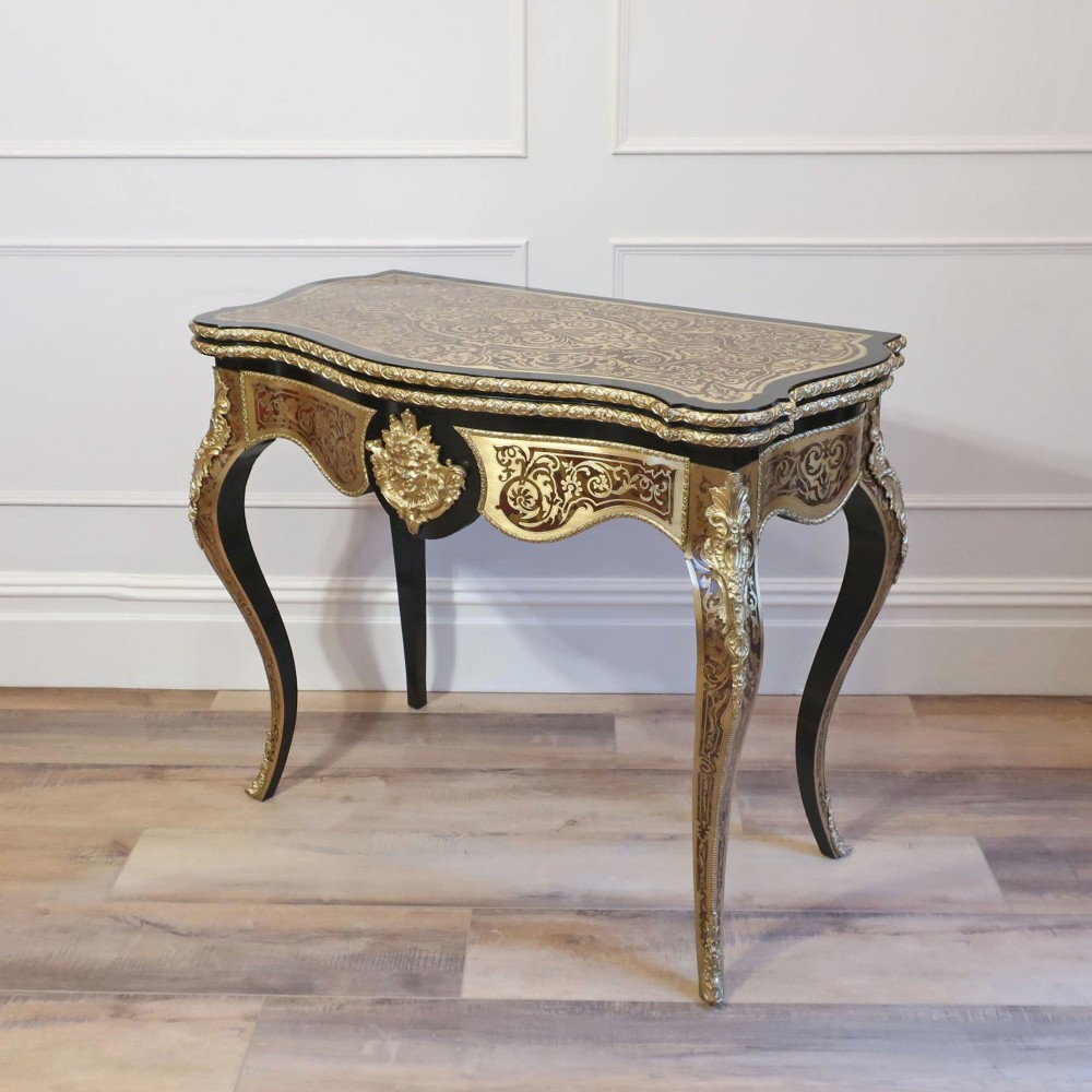 A French Louis XV style Boulle games table featuring brass and tortoiseshell marquetry, gilded ormolu mounts, and cabriole legs.