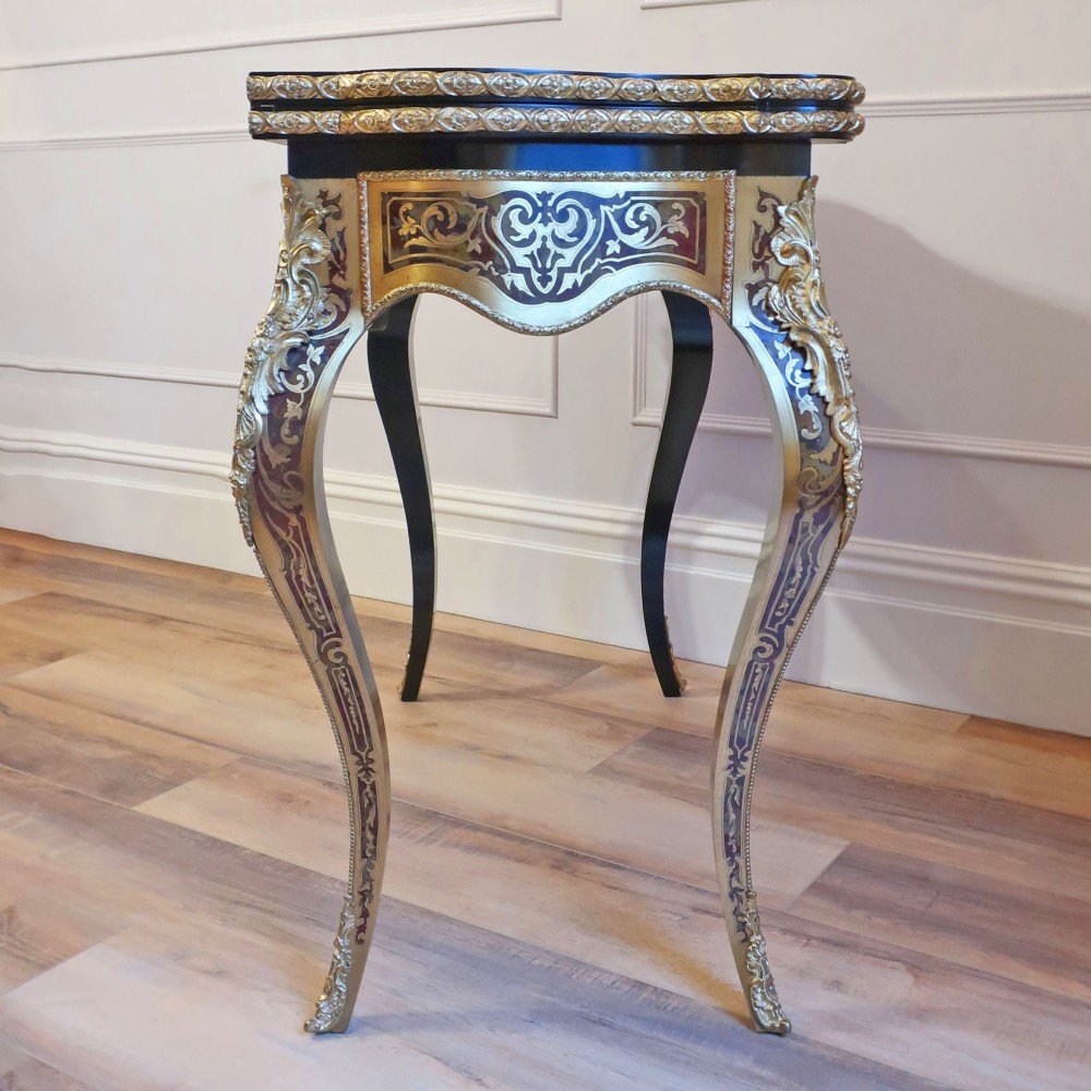 A French Louis XV style Boulle games table featuring brass and tortoiseshell marquetry, gilded ormolu mounts, and cabriole legs. View XIII