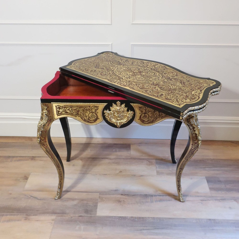 A French Louis XV style Boulle games table featuring brass and tortoiseshell marquetry, gilded ormolu mounts, and cabriole legs. View XV