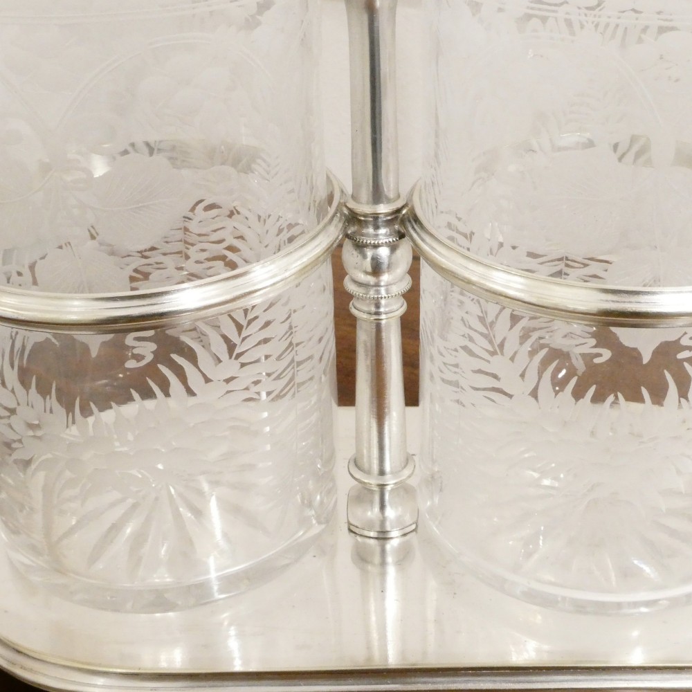 A Victorian silver-plated decanter stand with a central arched handle holding three etched glass decanters with stoppers. View III