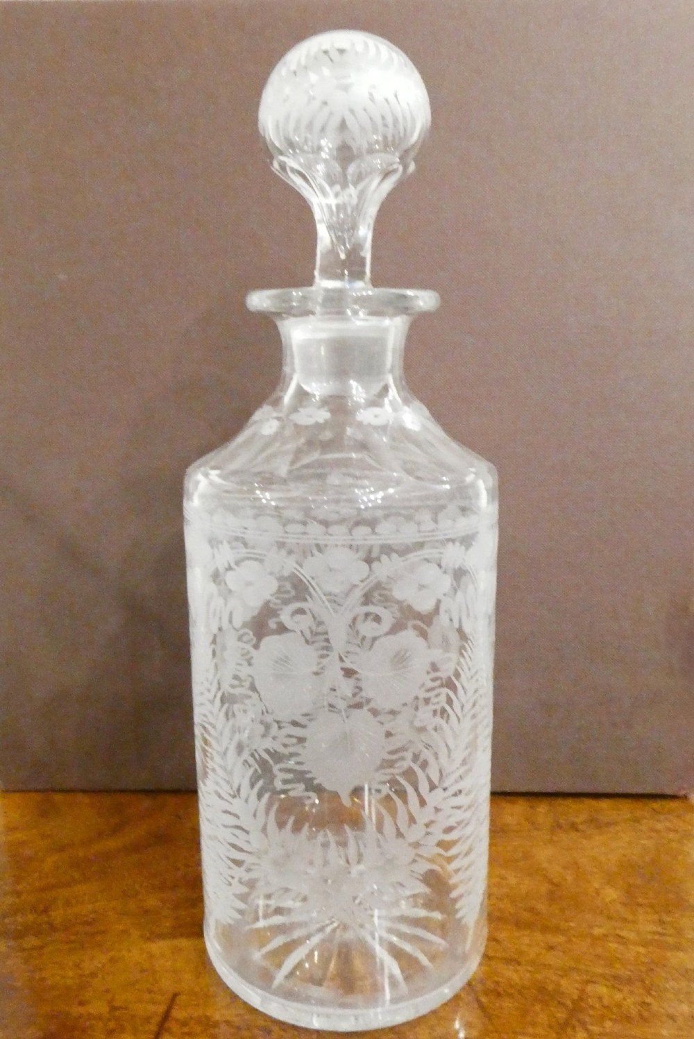 A Victorian silver-plated decanter stand with a central arched handle holding three etched glass decanters with stoppers. View V