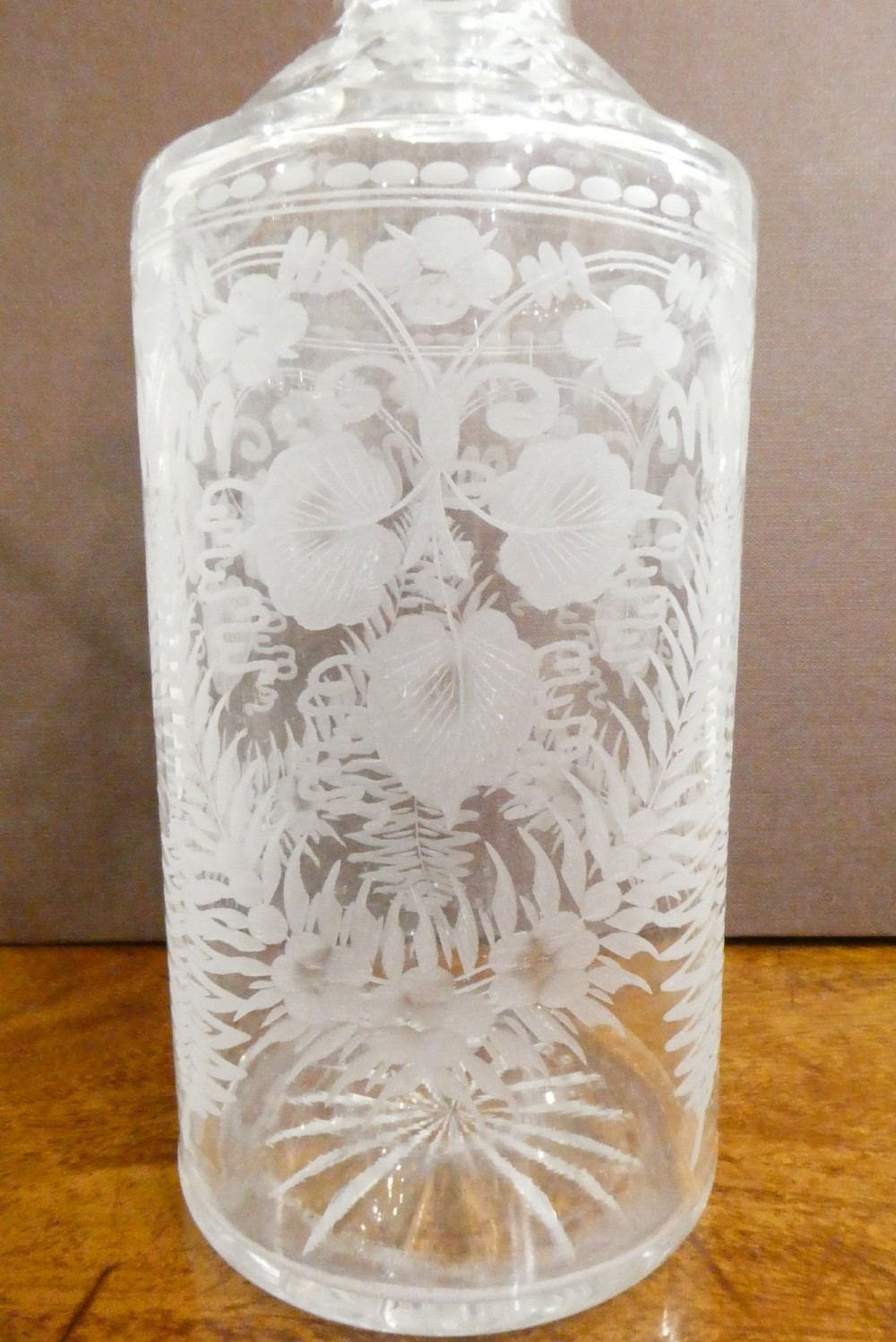 A Victorian silver-plated decanter stand with a central arched handle holding three etched glass decanters with stoppers. View VI