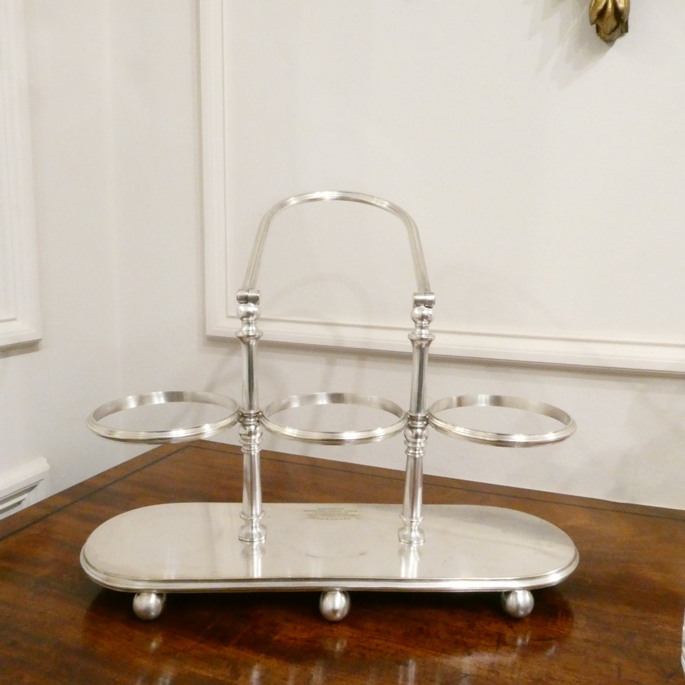 A Victorian silver-plated decanter stand with a central arched handle holding three etched glass decanters with stoppers. View XI