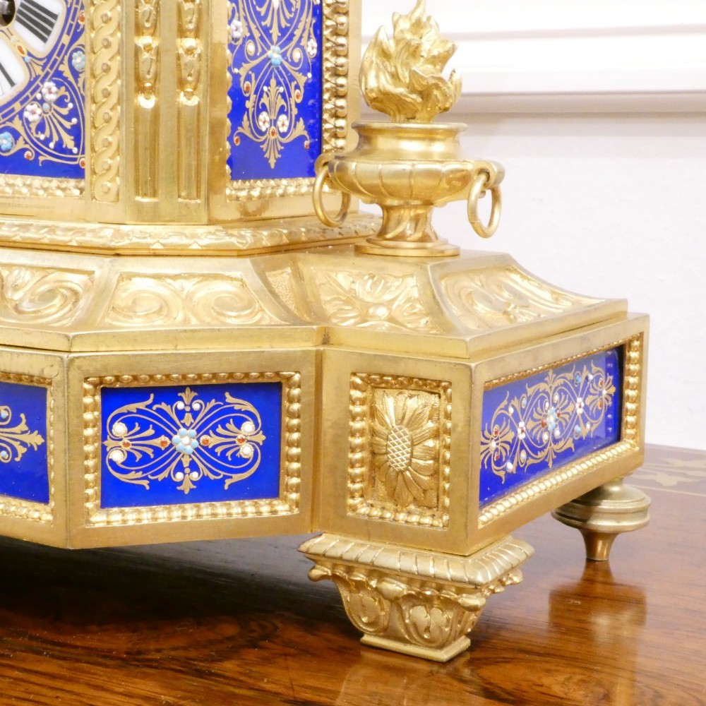 A French gilt bronze mantel clock featuring two cherub figures atop an ornate golden structure with cobalt blue porcelain panels and Roman numerals. View V