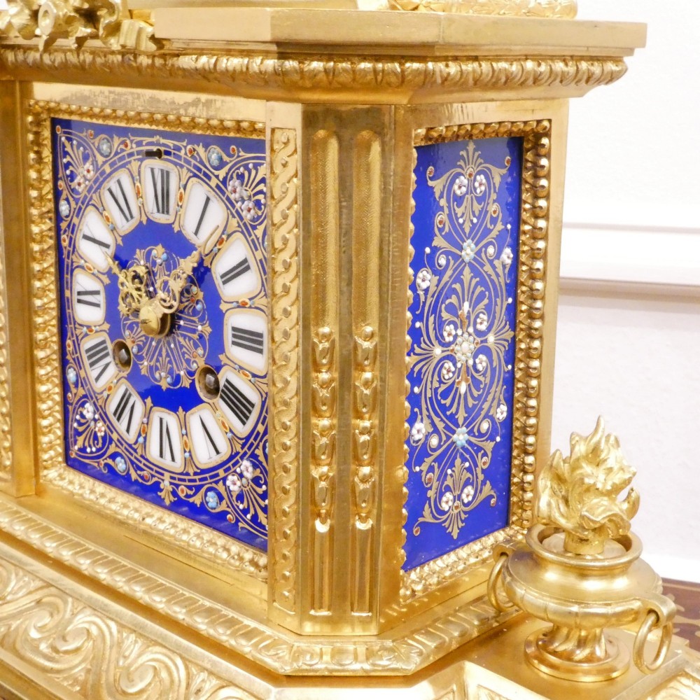 A French gilt bronze mantel clock featuring two cherub figures atop an ornate golden structure with cobalt blue porcelain panels and Roman numerals. View VII