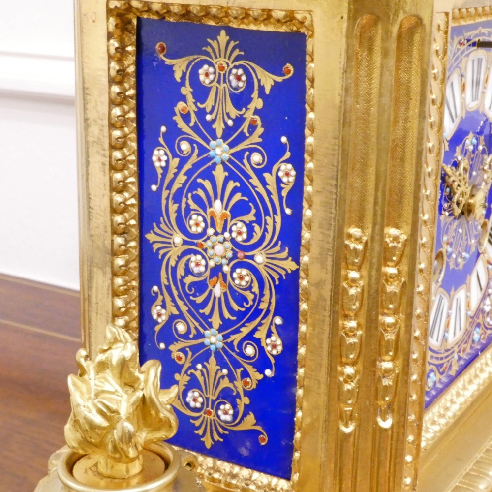 A French gilt bronze mantel clock featuring two cherub figures atop an ornate golden structure with cobalt blue porcelain panels and Roman numerals. View XI