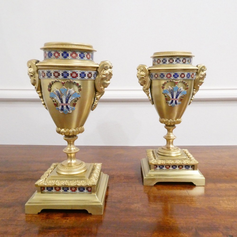 A nineteenth-century French gilt brass mantel clock featuring colourful champleve enamel geometric patterns, flanked by two matching decorative urns. View XII