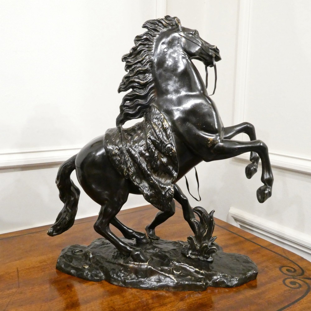 A pair of patinated dark bronze sculptures depicting rearing horses held by grooms on naturalistic bases. View VII