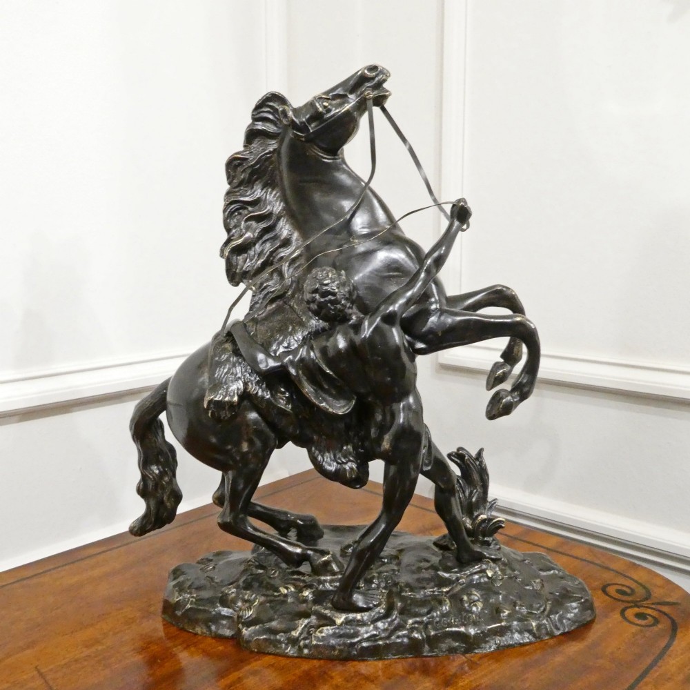 A pair of patinated dark bronze sculptures depicting rearing horses held by grooms on naturalistic bases. View VIII