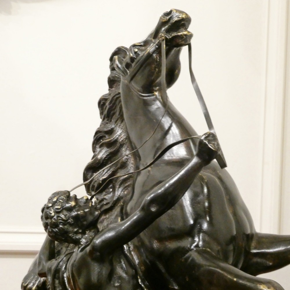 A pair of patinated dark bronze sculptures depicting rearing horses held by grooms on naturalistic bases. View IX