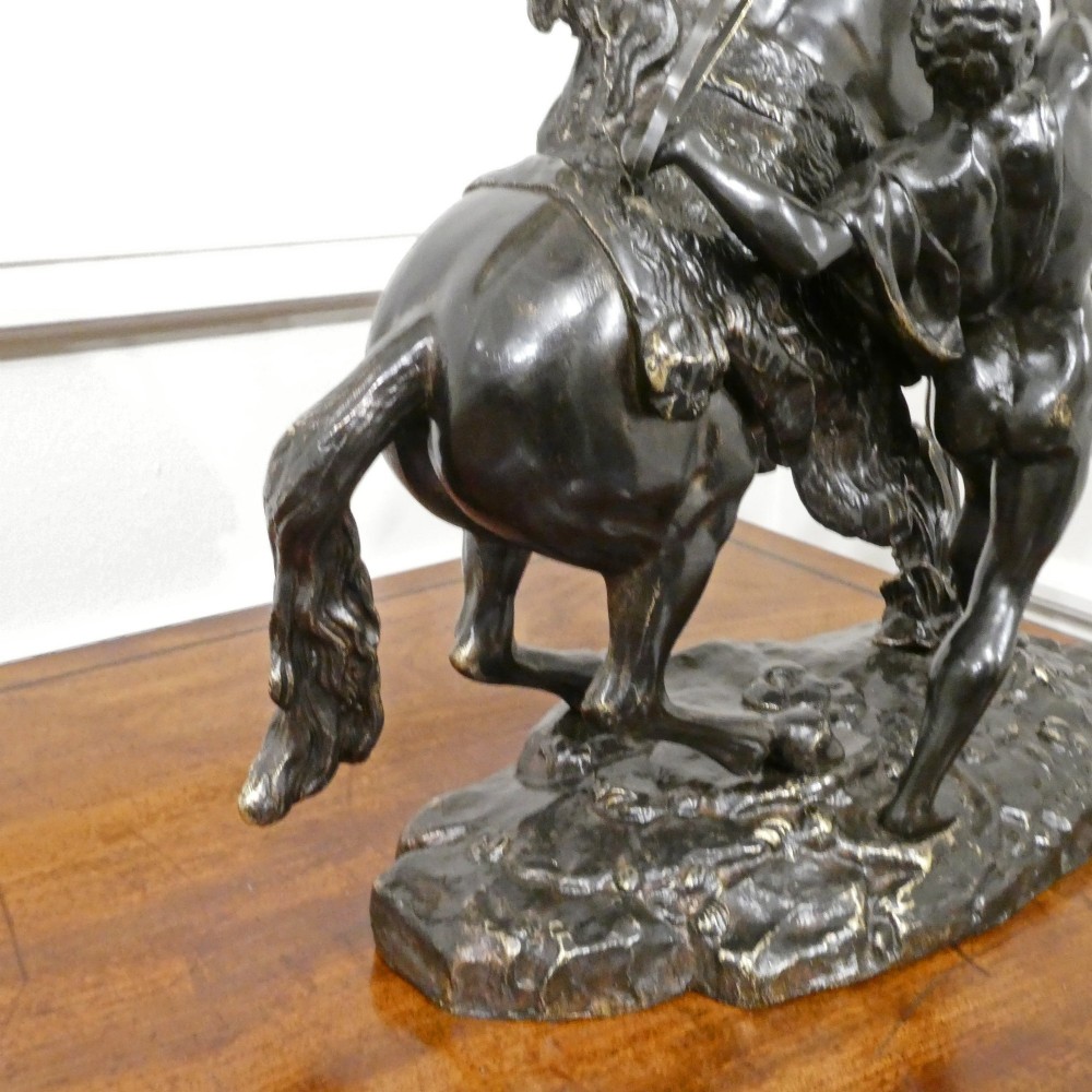 A pair of patinated dark bronze sculptures depicting rearing horses held by grooms on naturalistic bases. View X