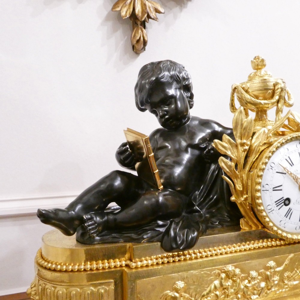 A 19th-century French gilt bronze mantel clock featuring a dark patinated bronze cherub seated beside a circular enamel dial atop a gilt relief base. View IV