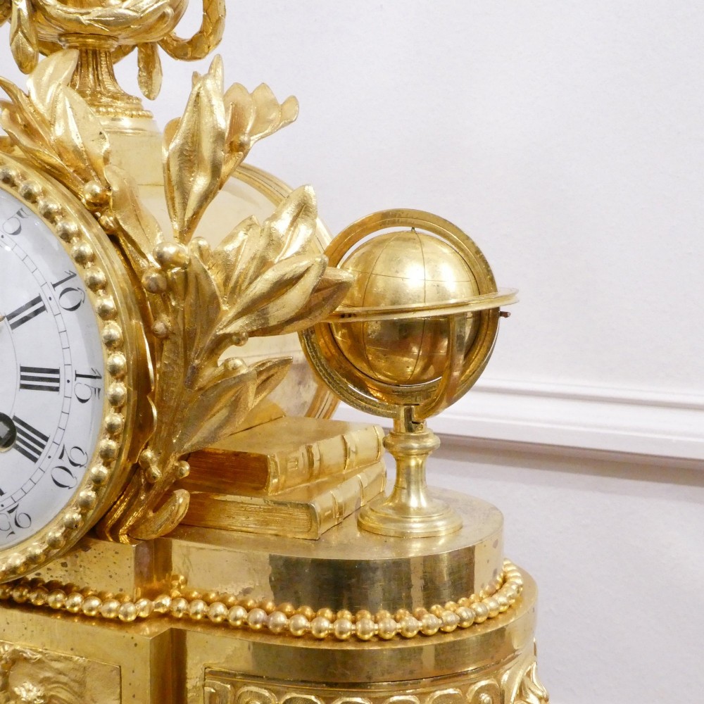 A 19th-century French gilt bronze mantel clock featuring a dark patinated bronze cherub seated beside a circular enamel dial atop a gilt relief base. View VI