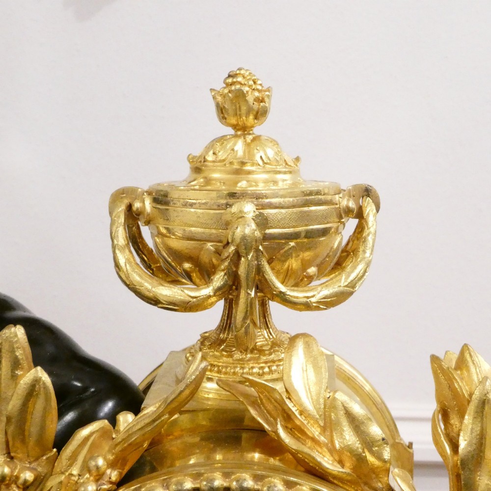 A 19th-century French gilt bronze mantel clock featuring a dark patinated bronze cherub seated beside a circular enamel dial atop a gilt relief base. View VII