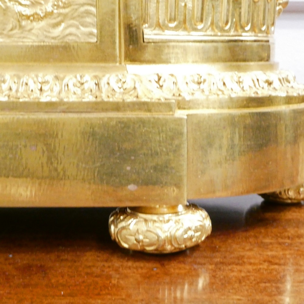 A 19th-century French gilt bronze mantel clock featuring a dark patinated bronze cherub seated beside a circular enamel dial atop a gilt relief base. View X