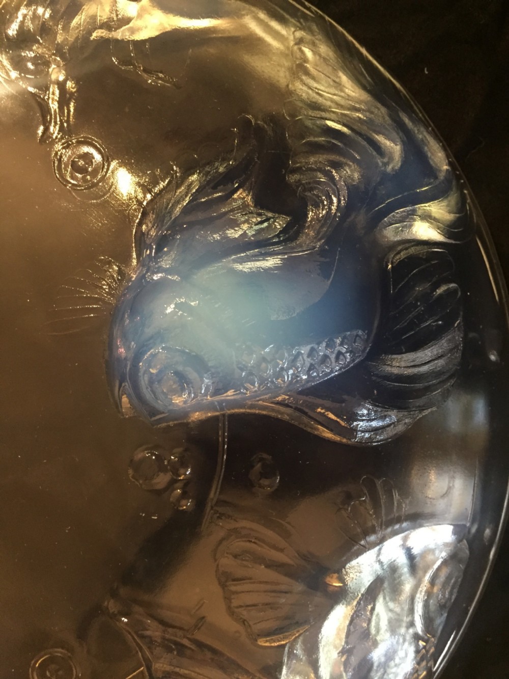 A circular Art Deco opalescent glass charger featuring relief-moulded fish and bubble motifs arranged in a continuous radial pattern. View V